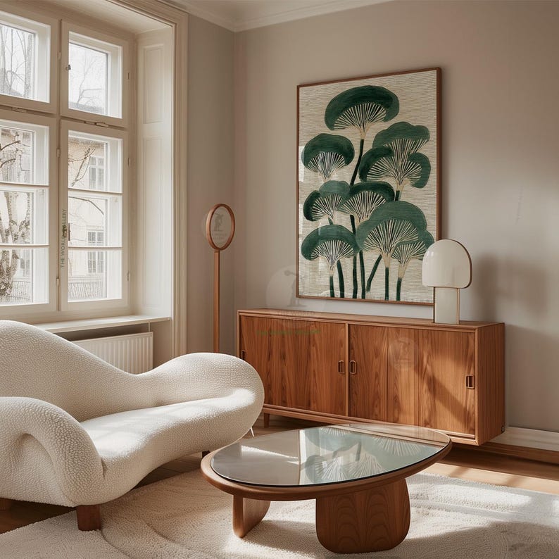May include: A living room scene featuring a cream-colored, curved sofa, a wooden coffee table with a glass top, and a wooden cabinet. A framed artwork with green mushroom illustrations hangs on the wall, complemented by a modern lamp.