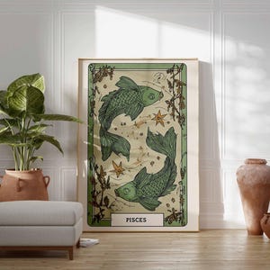 May include: A framed art print featuring two green fish, stars, and botanical elements, labeled "PISCES." The artwork has a vintage aesthetic with a cream-colored background and a green border. The print is displayed on a wooden floor.