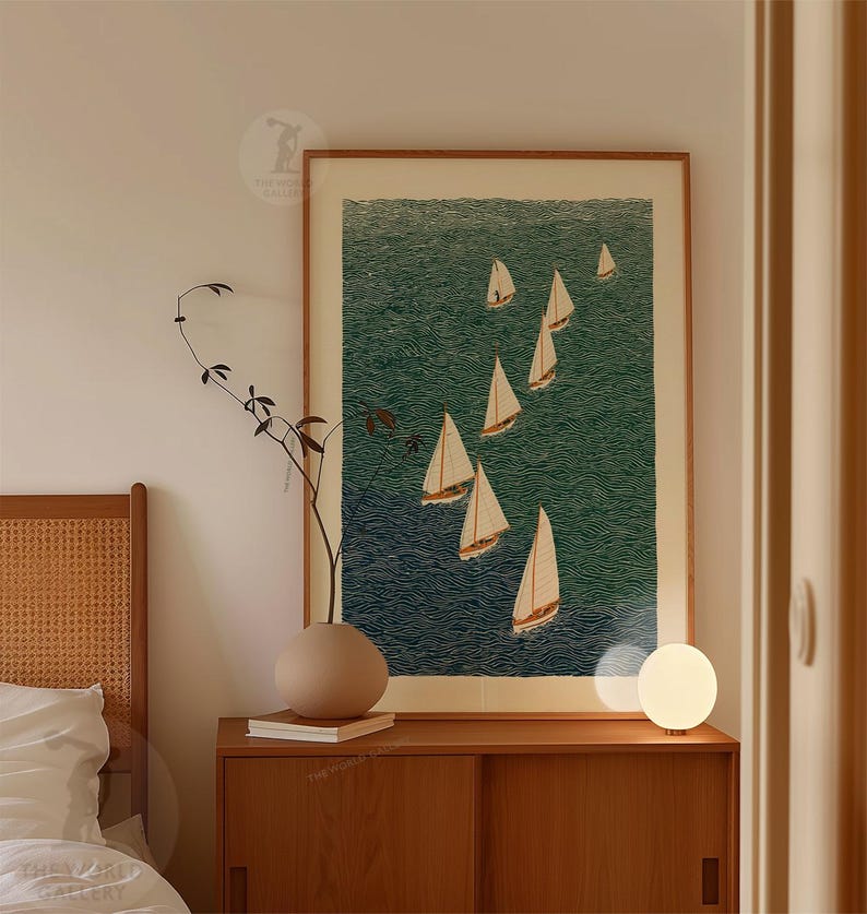 May include: A framed art print featuring a nautical scene with several sailboats on a textured teal-green sea. The artwork is displayed above a wooden cabinet, with a decorative vase and a small lamp.