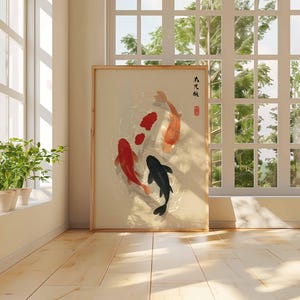 Puede incluir: Una obra de arte enmarcada que representa una escena de estanque de carpas koi con tres carpas koi rojas, naranjas y negras. La obra de arte se exhibe en una habitaci&oacute;n con una ventana y luz natural. La obra de arte tiene caracteres japoneses.