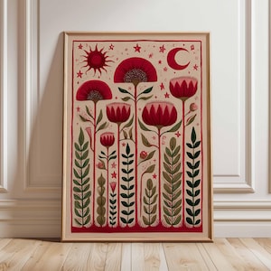 May include: A framed art print featuring a stylized floral design. The artwork showcases red flowers, green foliage, a sun, moon, and stars against a beige background. The print is encased in a wooden frame, adding a touch of warmth to the botanical theme.