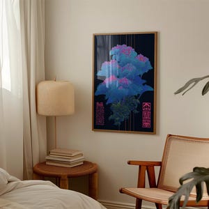 May include: A framed art print featuring a vibrant, abstract floral design in shades of blue and pink against a dark background. The artwork includes vertical gold lines and text in pink. The frame is a natural wood color.