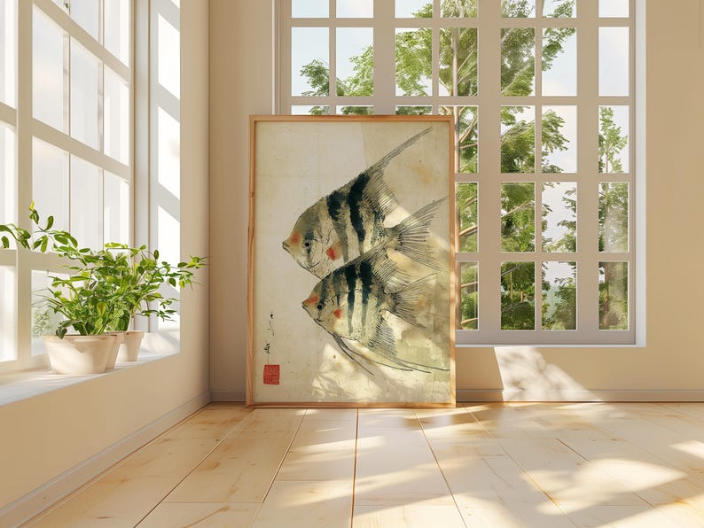 K&ouml;nnte beinhalten: Ein gerahmter Aquarelldruck mit zwei stilisierten Fischen mit schwarz-wei&szlig;en Streifen und roten Akzenten. Das Kunstwerk wird in einem hellen Raum mit einem Fenster und Pflanzen ausgestellt, was eine ruhige Atmosph&auml;re schafft. Der Druck hat einen Holzrahmen.