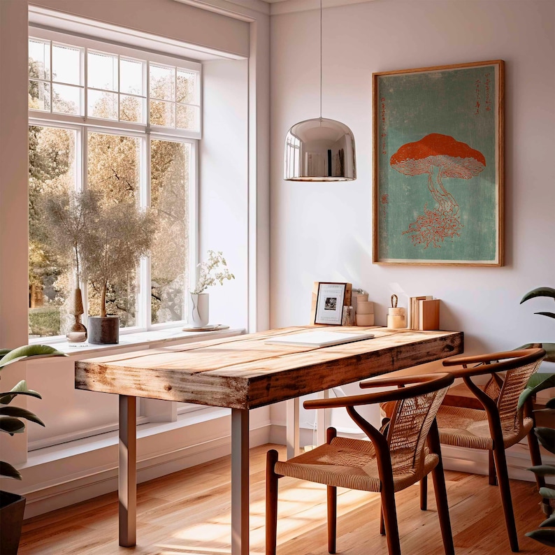 May include: A light-filled room with a wooden desk and two chairs. A framed mushroom print hangs on the wall. A large window offers a view of trees. A silver pendant light hangs above the desk. Plants and decor add to the room's aesthetic.
