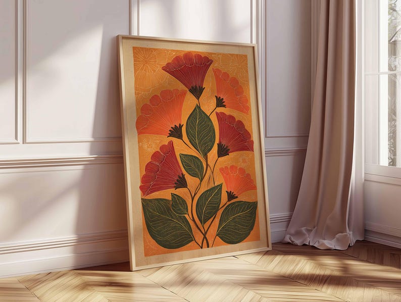 May include: A framed floral art print featuring stylized red and orange flowers with green leaves against an orange background. The artwork is in a light wooden frame and leans against a white wall and wooden floor.