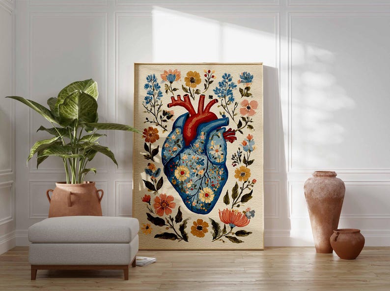 May include: A framed art print featuring a stylized anatomical heart design. The heart is blue with floral patterns and red arteries, surrounded by colorful flowers. The artwork is displayed in a room with a plant, ottoman, and decorative vases.