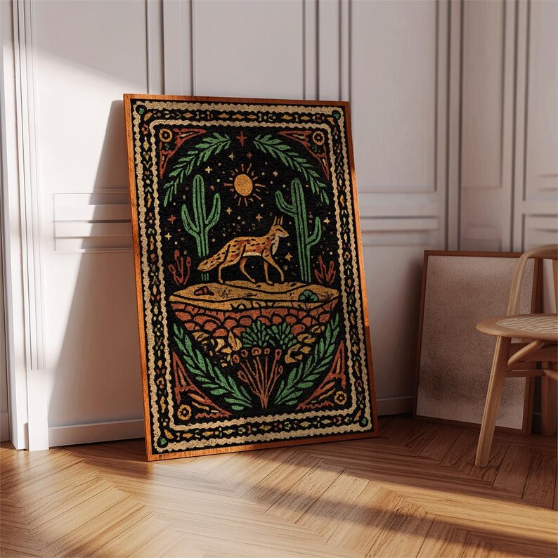 May include: A framed art print featuring a desert scene with a fox, cacti, and sun. The artwork has a black background with orange, green, and yellow details. The frame is a warm brown color, and the print is leaning against a white wall.