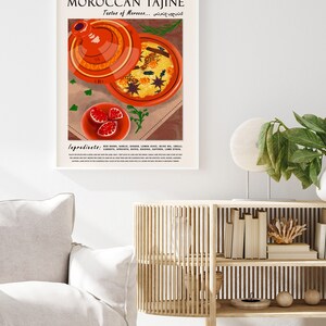 May include: A poster with a colorful illustration of a Moroccan tagine, a traditional clay pot used for cooking. The poster features the text "Moroccan Tajine" and "Taste of Morocco..." in a modern font. The ingredients for the dish are listed below the image.