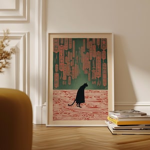 May include: Framed art print featuring a black cat silhouette in a Japanese-inspired scene. The artwork has a green and red color palette, with hanging lanterns and a water-like pattern. The print is displayed on a wooden floor.