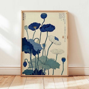 May include: A framed art print featuring a botanical illustration of blue and white poppies. The artwork has a vintage aesthetic, with detailed depictions of the flowers and foliage against a cream background. The frame is made of light-colored wood.