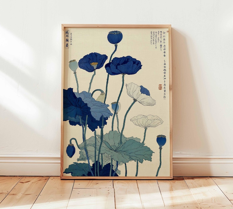 May include: A framed art print featuring a botanical illustration of blue and white poppies. The artwork has a vintage aesthetic, with detailed depictions of the flowers and foliage against a cream background. The frame is made of light-colored wood.