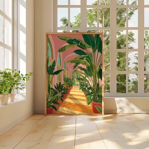 May include: A framed art print depicts a sunlit hallway lined with potted plants and archways. The artwork features a pink sky, orange floor, and green foliage. The scene is set in a room with a large window and potted plants on the windowsill.