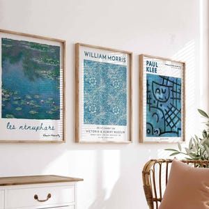 May include: Three framed art prints with wooden frames displayed on a white wall. The prints showcase artwork by Claude Monet, William Morris, and Paul Klee. The Monet print depicts water lilies, the Morris print has a blue floral pattern, and the Klee print has a blue abstract design.