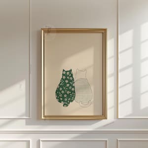 Puede incluir: Impresi&oacute;n art&iacute;stica enmarcada con dos gatos estilizados. Uno es verde con un estampado floral blanco, el otro gris claro con un patr&oacute;n de cuadr&iacute;cula. La obra est&aacute; enmarcada en dorado sobre un fondo beige.