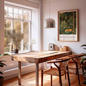 Puede incluir: Una habitaci&oacute;n con un escritorio de madera y dos sillas. Un cuadro enmarcado de Henri Rousseau cuelga en la pared. El cuadro representa un tigre en una escena de la jungla. Una gran ventana ofrece vistas de &aacute;rboles.