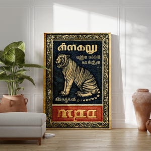 May include: A framed artwork featuring a tiger illustration in gold against a dark blue background. The artwork includes text in a foreign language and is framed with a gold border. The artwork is displayed in a room with a plant, ottoman, and decorative vases.