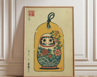 Könnte beinhalten: Gerahmter Kunstdruck mit einer Daruma-Puppe. Die Illustration zeigt eine traditionelle japanische Daruma-Puppe mit Blumen- und Wellenmustern auf einem gelben, tagförmigen Hintergrund. Enthält japanischen Text und eine schwarze Kordel.