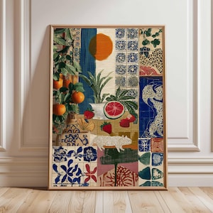 May include: A framed art print with a collage design. The artwork features oranges, strawberries, a white cat, and a sliced grapefruit. The background includes blue, orange, and patterned tiles, creating a vibrant and eclectic composition.