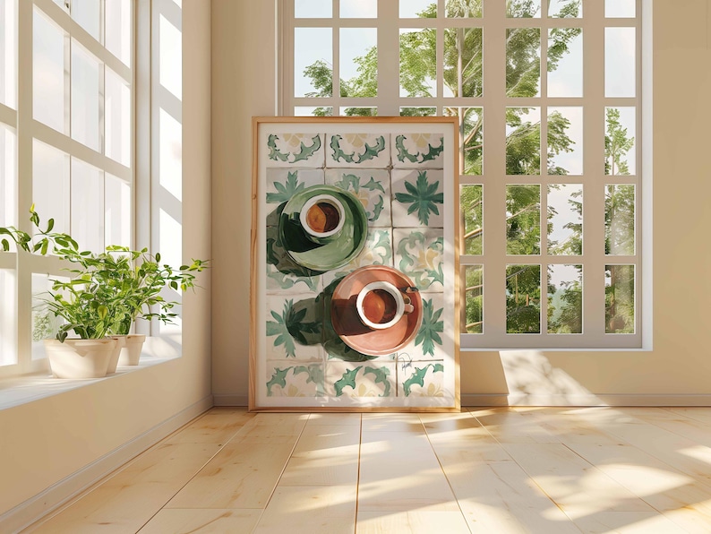 May include: A framed artwork featuring two cups of coffee on saucers, one green and one coral, set against a backdrop of decorative tiles. The artwork is displayed in a sunlit room with a window and potted plants.