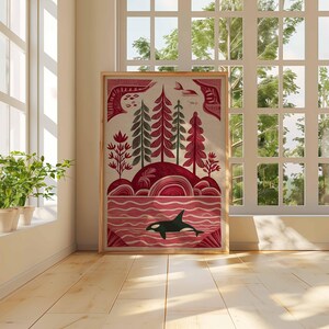 May include: A framed art print featuring a stylized landscape with a red and green color palette. The artwork depicts trees, hills, and an orca in the water. The print is displayed in a room with a window and plants.