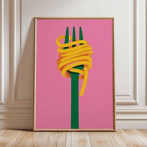Op de afbeelding: Een ingelijste kunstdruk met een groene vork met gele spaghetti eromheen. De achtergrond is effen roze. Het kunstwerk wordt tentoongesteld op een houten vloer tegen een witte muur.