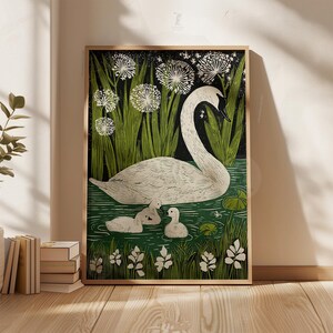 May include: A framed art print featuring a white swan with three cygnets swimming in a pond. The artwork has a black background with green reeds and white flowers. The print is in a wooden frame.