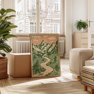 May include: A framed landscape art print featuring a mountain range, river, and trees in green and beige tones. The artwork has a vintage aesthetic and is displayed in a bright, airy room with a large window.
