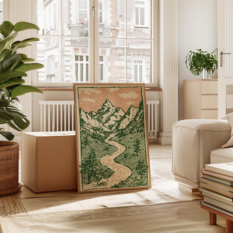 May include: A framed landscape art print featuring a mountain range, river, and trees in green and beige tones. The artwork has a vintage aesthetic and is displayed in a bright, airy room with a large window.