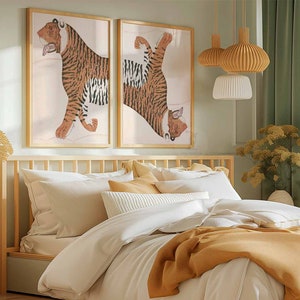 Peut inclure: Deux illustrations encadr&eacute;es de tigres dans une chambre &agrave; coucher. Les illustrations sont de style minimaliste avec un fond brun clair et les tigres sont repr&eacute;sent&eacute;s en orange et noir. La chambre &agrave; coucher comprend un cadre de lit en bois avec une literie blanche et une couverture jaune. Il y a deux luminaires suspendus avec des abat-jours blancs et bruns.