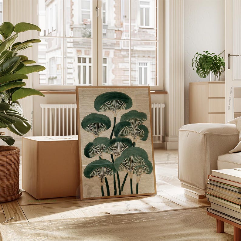 May include: A framed art print featuring a stylized illustration of dark green mushroom-like shapes against a beige background. The artwork is displayed in a light-toned wooden frame, leaning against a wall in a well-lit room. The overall theme is nature and botanical art.