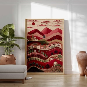 May include: A framed art print showing a stylized landscape in shades of red, pink, and green. The artwork features a village with white buildings, trees, and a red sun. The print is displayed with a large potted plant, a footstool, and decorative vases.