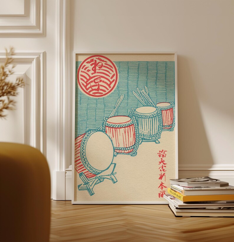 May include: A framed print featuring a Japanese-style illustration of four drums in red and blue, with drumsticks. A red circular emblem is at the top left. The background is light blue with vertical lines. Japanese text is at the bottom right.