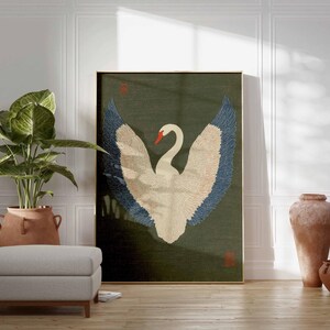 Pode incluir: Uma obra de arte emoldurada com um cisne branco com asas azuis e bege sobre um fundo verde escuro. A obra de arte &eacute; exibida em uma sala com uma planta em vaso, um pufe cinza e vasos de terracota. A sala tem pain&eacute;is brancos e um ch&atilde;o de madeira.