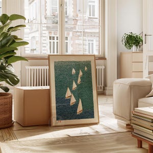May include: A framed art print featuring a nautical scene with several sailboats on a teal-colored sea. The sailboats have white sails and are set against a textured background. The print is in a wooden frame and leans against a wall.