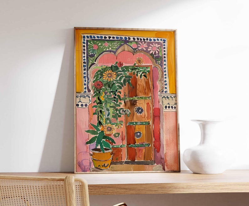 May include: A watercolor painting of a colorful doorway with a pink archway, a wooden door, and a potted plant. The door is decorated with green, blue, and yellow details. The painting is framed in a yellow frame.