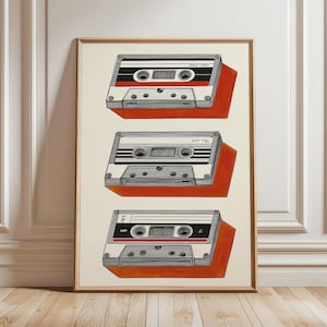 Puede incluir: Una impresión enmarcada con tres cintas de cassette retro. Cada cinta está representada con un cuerpo blanco, detalles en negro y rojo, y un efecto de sombra. La obra de arte está sobre un fondo crema.
