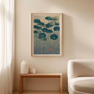 May include: Framed art print featuring a serene pond scene with large, dark teal lily pads and a small orange fish. The artwork has a vintage aesthetic, with a light wooden frame. The print is displayed above a wooden table with white vases.
