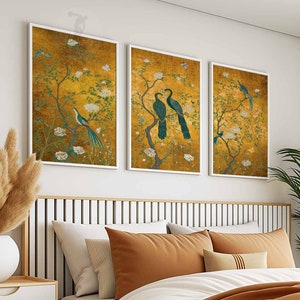 May include: Three framed prints with a gold background and floral designs. Each print features a pair of birds with long, flowing tails. The birds are depicted in shades of blue and green.