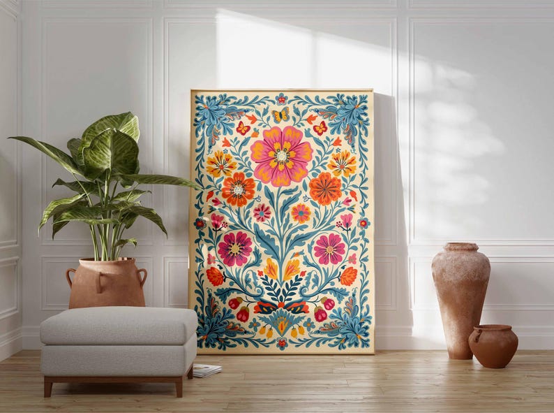 Op de afbeelding: Een kleurrijk bloemenbehang met een cr&egrave;mekleurige achtergrond, met een grote roze bloem in het midden omringd door kleinere oranje, roze en blauwe bloemen. De behang is ingelijst in een gouden lijst en hangt aan een witte muur.