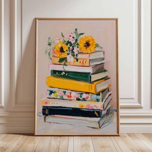 May include: A framed painting of a stack of books with a bouquet of sunflowers and other flowers on top. The books have various colored spines, including yellow, green, and floral patterns. The background is a soft pink.