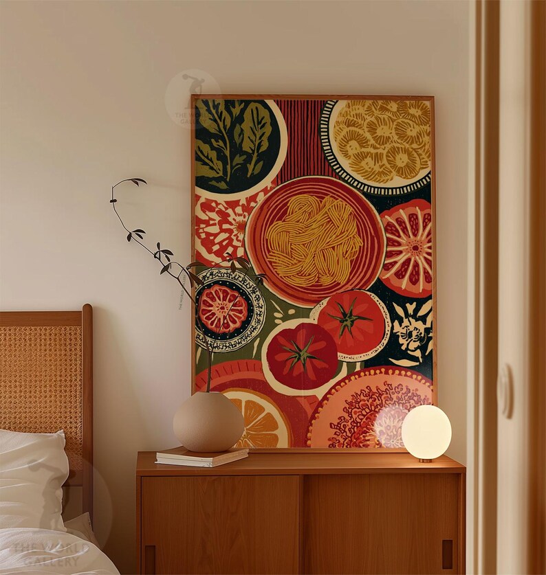 May include: A framed art print featuring a colorful still life of food items. The artwork includes images of tomatoes, oranges, pasta, and other food elements in a vibrant, eye-catching design. The print is displayed on a wooden cabinet.