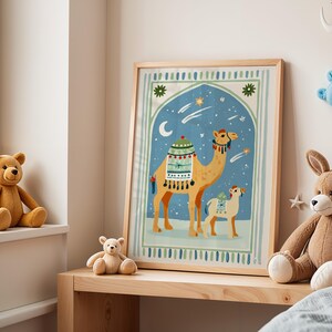 May include: A framed art print featuring a camel and a baby camel against a blue night sky with stars and a crescent moon. The artwork is in a wooden frame and is displayed on a wooden shelf. Teddy bears and a stuffed bunny are also visible.