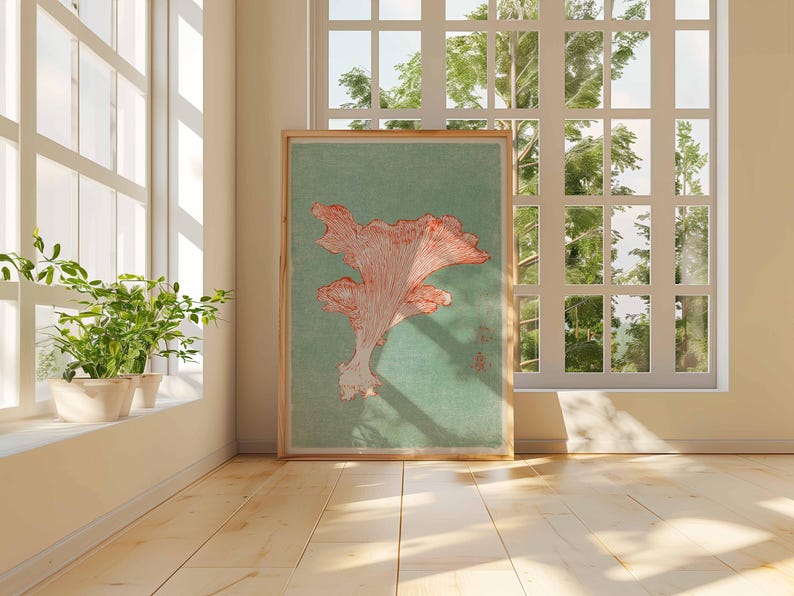 May include: A framed botanical print featuring a coral-colored mushroom illustration on a teal background. The artwork is displayed on a wooden floor, next to a window with natural light and potted plants.