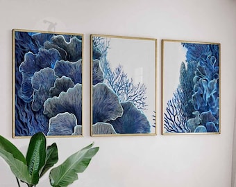 Può includere: Tre stampe artistiche incorniciate con disegni astratti di barriera corallina blu. L'opera d'arte ha una cornice dorata ed è esposta su una parete bianca. Il corallo è raffigurato in tonalità di blu con riflessi bianchi.