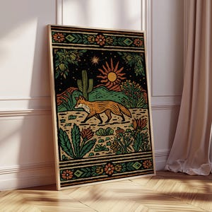 May include: Framed art print featuring a stylized desert landscape with a fox. The artwork showcases a fox in shades of orange and brown, set against a backdrop of cacti, flowers, and a setting sun. The border is decorated with floral and geometric patterns.