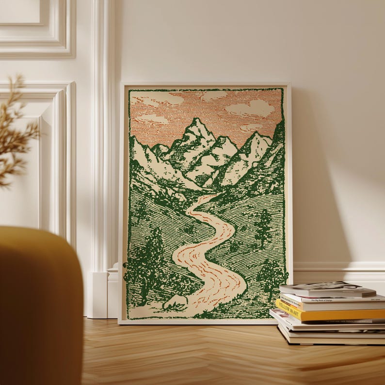 May include: A framed art print featuring a mountain landscape with a winding river. The artwork uses green and peach tones, with a vintage aesthetic. The print is displayed on a wooden floor, leaning against a white wall.