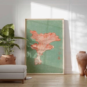 May include: A framed art print featuring a coral-colored mushroom illustration against a muted green background. The artwork is displayed in a room with a potted plant, a gray ottoman, and decorative pottery, creating a serene atmosphere.