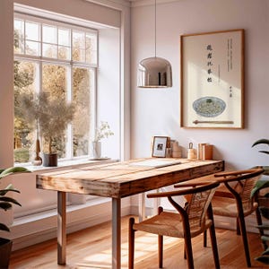 May include: A dining room scene featuring a wooden table with metal legs and two woven chairs. A framed artwork of noodles with chopsticks hangs on the wall. A large window offers a view of trees.