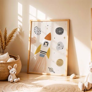 May include: A framed art print featuring a whimsical rocket ship with a cat pilot, surrounded by planets and stars. The illustration has a soft color palette with orange, yellow, and blue accents, perfect for a nursery or children's room.