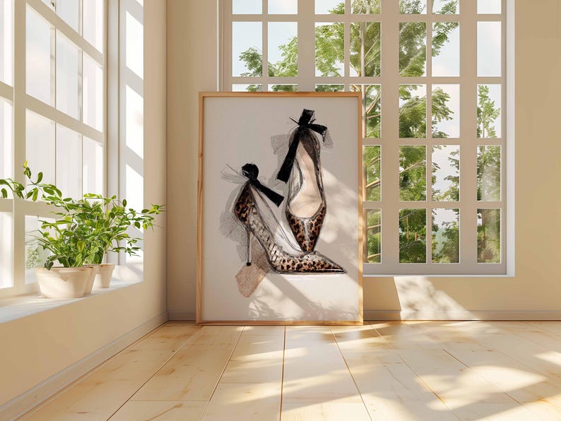 Op de afbeelding: Een ingelijste print van hoge hakken. Het kunstwerk toont twee elegante schoenen met spitse tenen en stilettohakken. E&eacute;n schoen heeft een luipaardprint, en beide hebben zwarte strikaccenten. De print wordt tentoongesteld in een kamer met natuurlijk licht.